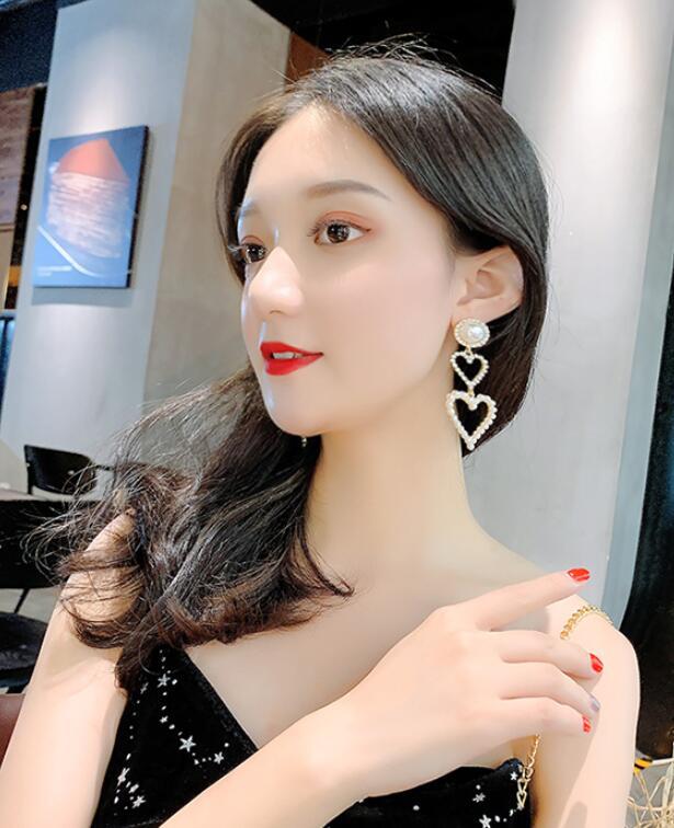 Woman wearing heart-shaped earrings in an indoor setting