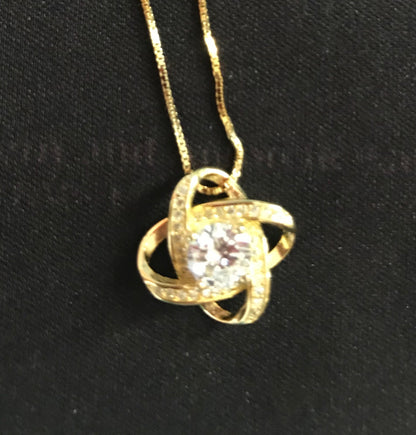 Gold necklace with a diamond pendant on a black background