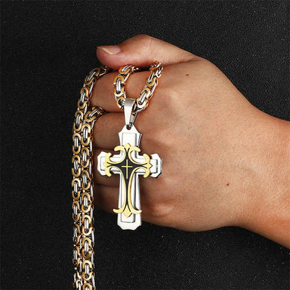 Hand holding a gold chain with a silver cross pendant against a black background